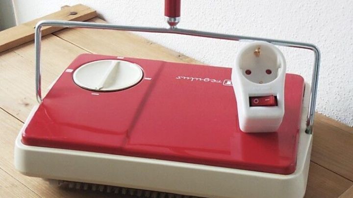 Ein rotes Ger&auml;t steht auf einem Tisch, w&auml;hrend es Strom misst, um im Haushalt effektiv Strom zu sparen.