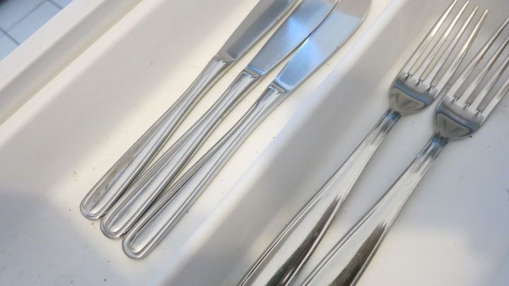 In einer wei&szlig;en Besteckschublade liegen ordentliche Edelstahl-Messer und -Gabeln, kein Anlaufen sichtbar.