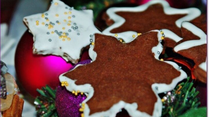 Schokoladige Nutella-Sterne liegen dekorativ auf einem festlichen Hintergrund aus bunten Weihnachtskugeln.