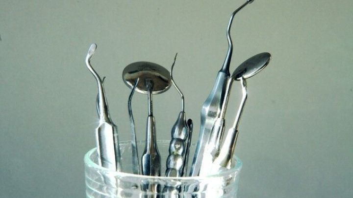 Eine Sammlung von Dentalinstrumenten steht in einem Glasbeh&auml;lter und ist bereit zur Verwendung bei zahn&auml;rztlichen Behandlungen.