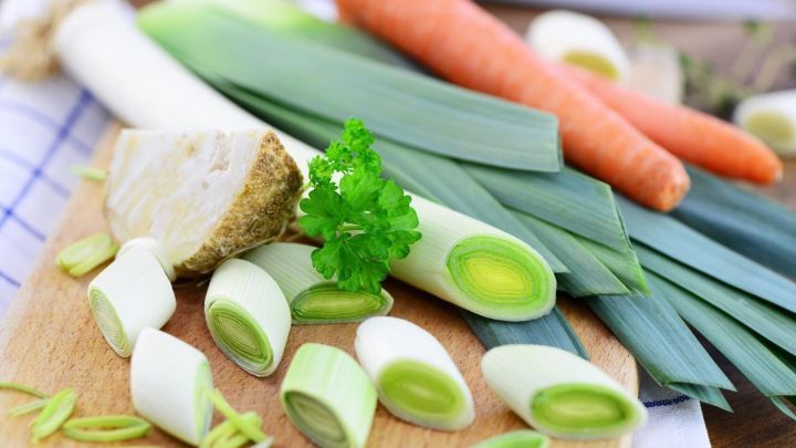 Auf einem Holzbrett liegen frisches Gem&uuml;se wie Lauch, Karotten und Petersilie, bereit zum Eingesalzen.