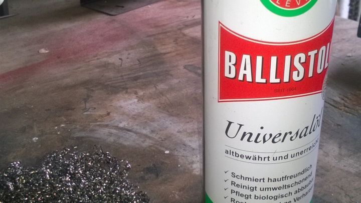 Eine Spraydose steht neben einem Haufen Stahlwolle, bereit zur Reinigung von Grillrost oder Backofen.
