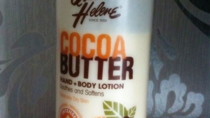 Eine Lotion mit der Aufschrift "Cocoa Butter" steht auf einem hellen Hintergrund, umgeben von dezentem Muster.