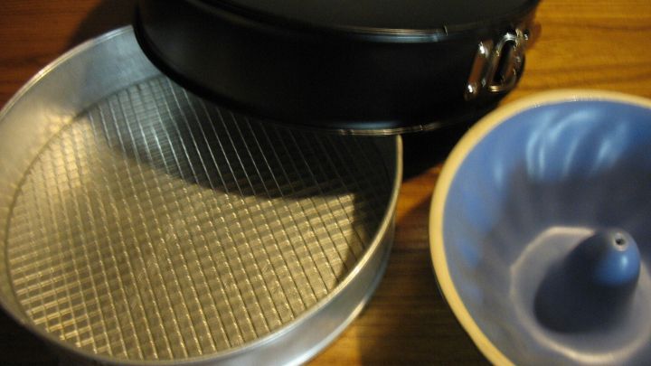 Zwei Backformen liegen auf einer Holzoberfl&auml;che, eine mit herausnehmbarem Boden und eine runde Form f&uuml;r Kuchen.