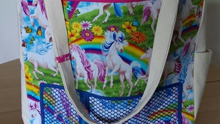 Eine bunte Spielzeugtasche mit Einhorn-Motiven steht auf einem Tisch und bietet viel Platz f&uuml;r Spielwaren und Zubeh&ouml;r.