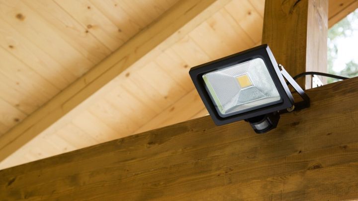 Eine LED-Lampe mit Bewegungsmelder ist an einem Holzrahmen befestigt und leuchtet in einem hellen Raum.