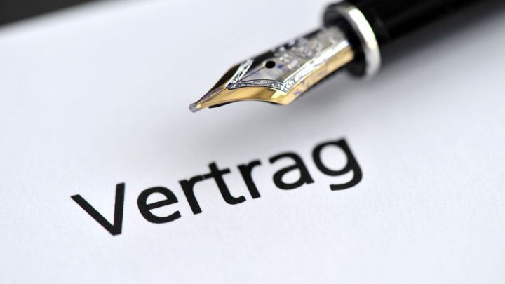 Ein F&uuml;llfederhalter liegt &uuml;ber einem Vertrag, der das Wort &bdquo;Vertrag&ldquo; deutlich zeigt, was Kaufentscheidungen am Messe verdeutlicht.