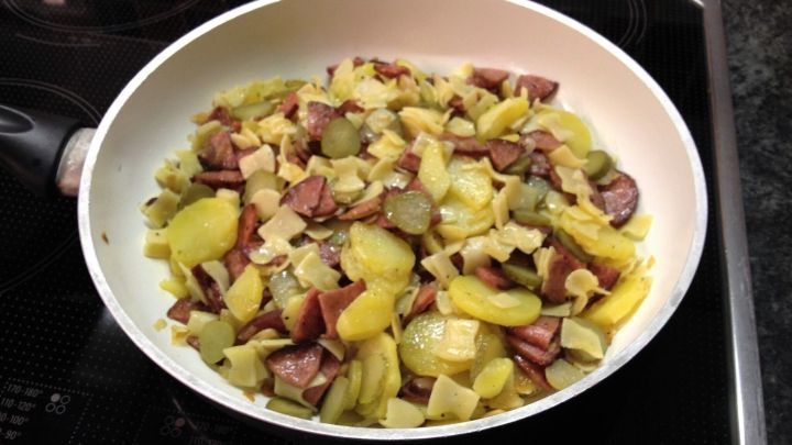 In einer Pfanne braten pikante Reste aus Kartoffeln, Wurst und Gew&uuml;rzgurken, um ein s&auml;ttigendes Essen zu kreieren.
