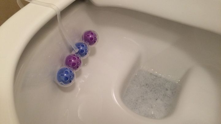 In einer Toilette schwimmen farbige WC Frisch Lavendel-Kugeln, w&auml;hrend sie Blasen im Wasser erzeugen und aktiv reinigen.