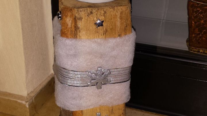 Die rustikale Kaminholz-Deko mit einer wei&szlig;en Kerze oben steht auf dem Boden und verleiht dem Raum eine gem&uuml;tliche Atmosph&auml;re.