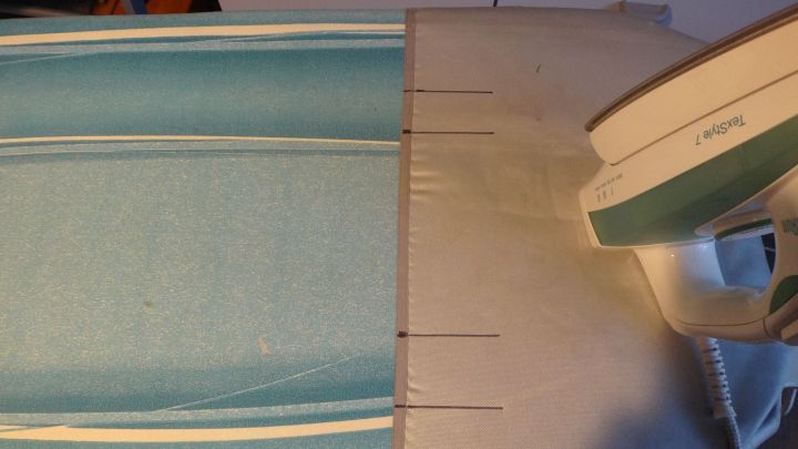 Ein B&uuml;geleisen gleitet &uuml;ber ein t&uuml;rkisfarbenes Tuch auf einem B&uuml;geltisch, w&auml;hrend es gegl&auml;ttet wird.