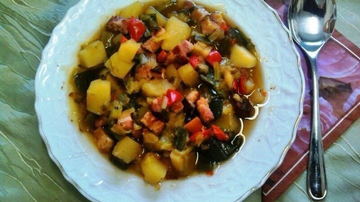 Ein dampfender Teller Porree-Gem&uuml;sesuppe mit buntem Gem&uuml;se und Kartoffeln auf einem eleganten Tischuntergrund.