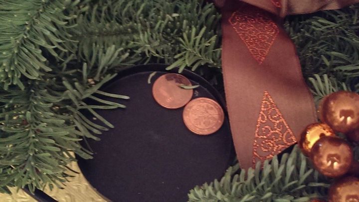 Auf dem Adventskranz stehen leicht schief Kerzen, umgeben von gr&uuml;nem Tannengr&uuml;n und dekorativem braunem Band.