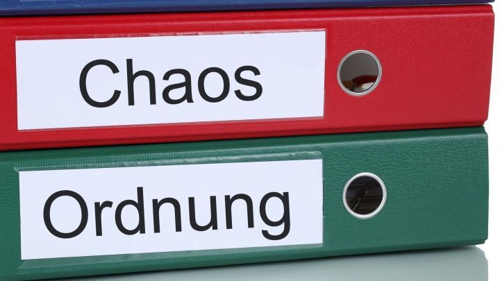 Ordner stehen nebeneinander, einer beschreibt "Chaos" und der andere "Ordnung", symbolisiert die Grundordnung im Haushalt.