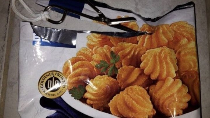 Ein Beutel mit Tiefk&uuml;hlkost, gef&uuml;llt mit vorgeformten Snacks, wird ohne Clip mit einer Schere ge&ouml;ffnet.