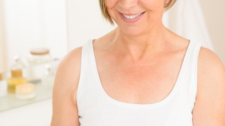 Eine &auml;ltere Frau tr&auml;gt eine Hautpflegecreme auf ihre Hand auf, w&auml;hrend sie im Badezimmer entspannende Pflege f&uuml;r den Winter genie&szlig;t.