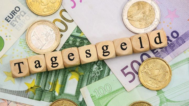 Holzbuchstaben formen das Wort "Tagesgeld" auf Euro-Scheinen und -M&uuml;nzen; finanzielle Darstellung.