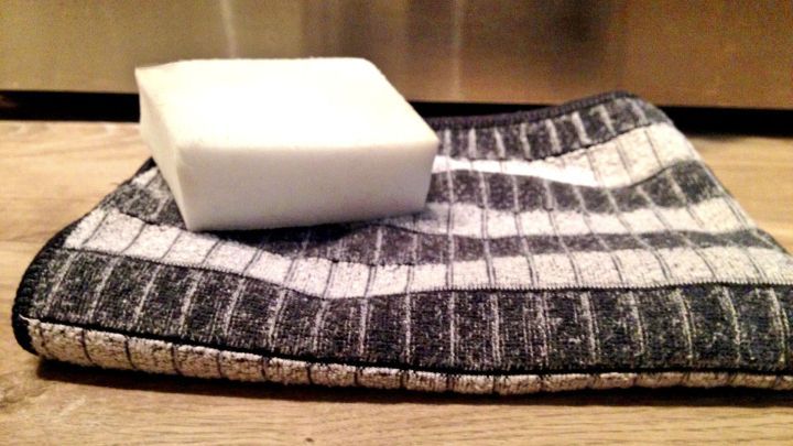 Eine elegante, hellgraue Seife liegt auf einem schwarzen und wei&szlig;en Geschirrtuch, bereit zur Reinigung von Edelstahloberfl&auml;chen.