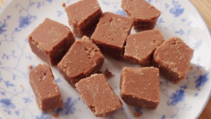 Kleine, quadratische Schokobonbons liegen auf einem dekorativen Teller, bereit zum Genie&szlig;en in einer gem&uuml;tlichen K&uuml;che.