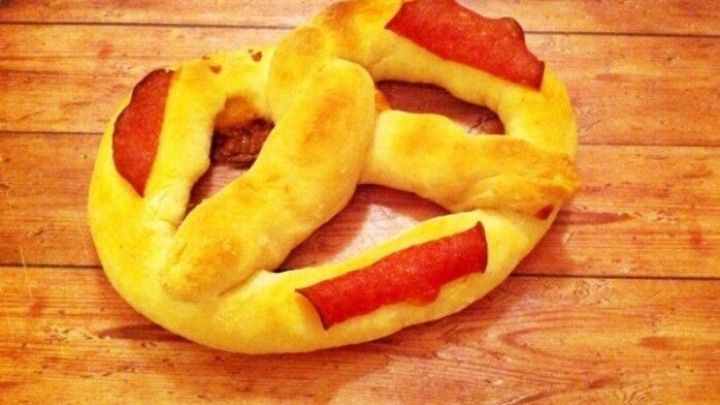 Ein frisch gebackenes Pizza Brezeln wird auf einem Holzbrett pr&auml;sentiert, umgeben von einer rustikalen K&uuml;chenszene.