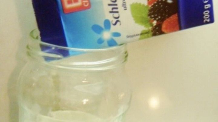 Eine Kartonverpackung mit Schlagsahne wird &uuml;ber ein Glas gesch&uuml;ttet, um abgelaufene Sahne in Butter zu verwandeln.