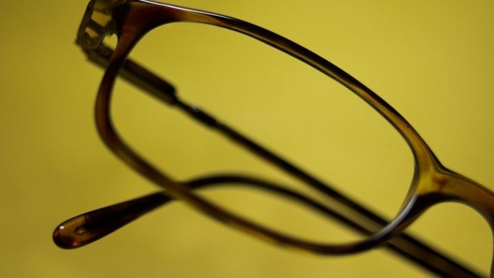 Eine Brille liegt auf einem gelben Hintergrund, w&auml;hrend sie zum Putzen bereitsteht und darauf wartet, gereinigt zu werden.