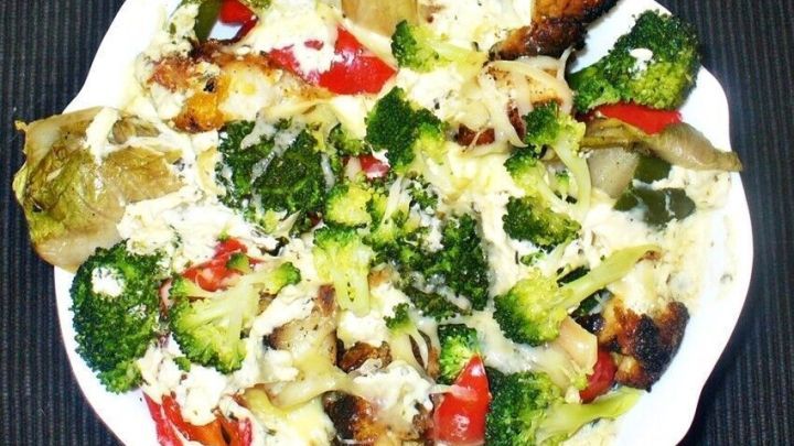 Ein bunten Teller mit &uuml;berbackenen Gem&uuml;se- und Bratfischresten, im Ofen knusprig gebacken, steht auf einem dunklen Untergrund.