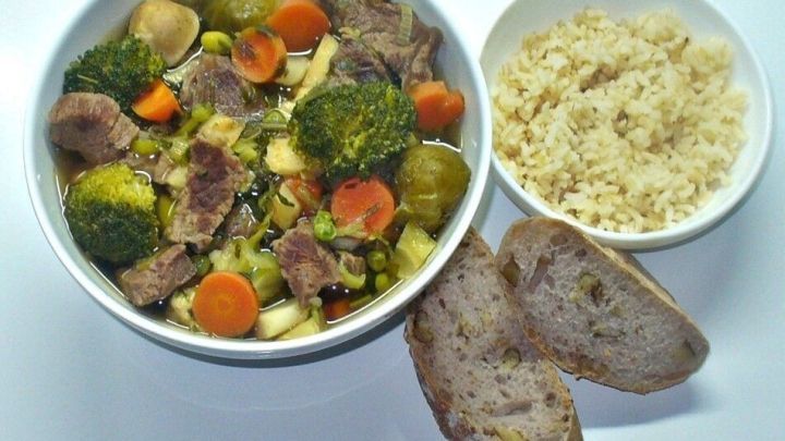 Eine bunte Sch&uuml;ssel scharfe Fr&uuml;hlingssuppe mit Rindfleisch und Gem&uuml;se sowie Beilagen von Couscous und Brot.