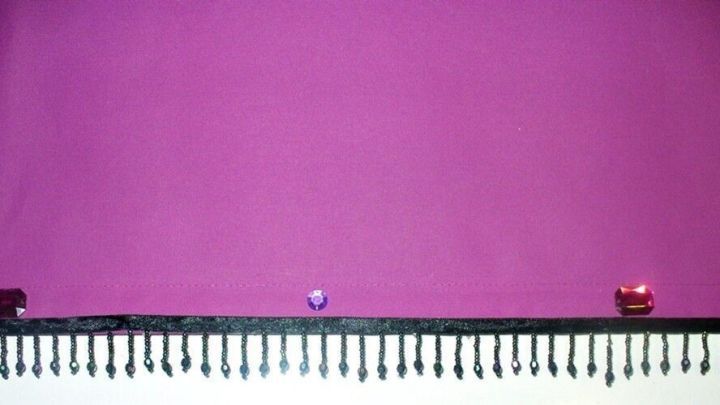 Zugrollos sind dekorativ gestaltet, mit Glitzersteinen auf einem lilafarbenen Hintergrund in einem stilvollen Raum.