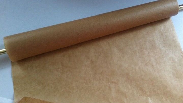 Ein St&uuml;ck Packpapier liegt auf einem Tisch und rollt sich teilweise ab, bereit f&uuml;r Notizen oder kreative Anwendungen.