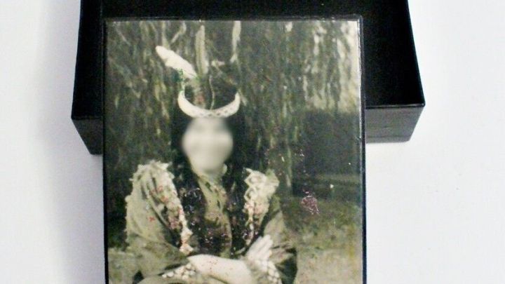 Eine individuell gestaltete Pappschachtel &ouml;ffnet sich, w&auml;hrend eine mysteri&ouml;se Figur darin sitzt und einen Vogel h&auml;lt.