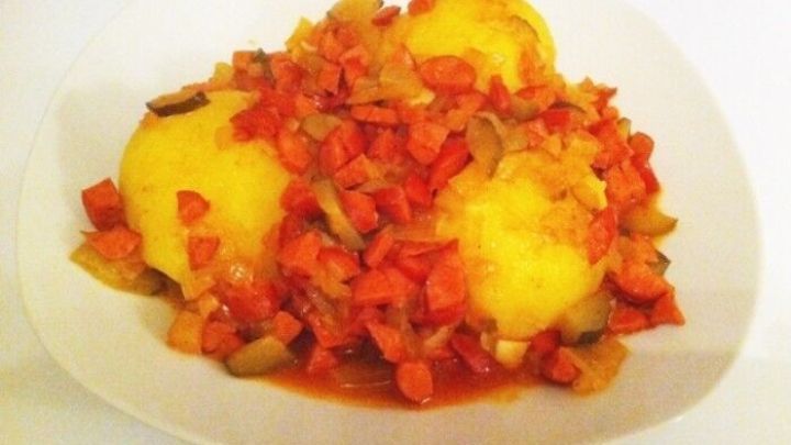 Gelbe Kn&ouml;del liegen auf einem Teller, &uuml;berzogen mit einer pikanten Debrecziner So&szlig;e aus frischem Gem&uuml;se.