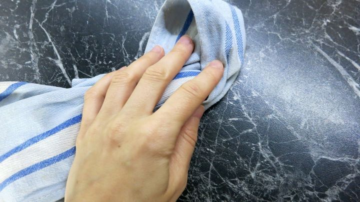 Ein Handtuch reinigt eine glatte Oberfl&auml;che, w&auml;hrend Essig verwendet wird, um Schmutz effektiv zu entfernen.