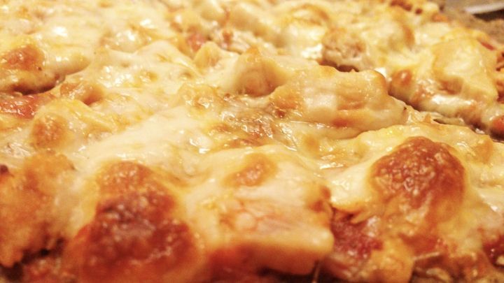 Eine glutenfreie Thunfischpizza aus Buchweizenmehl ist im Detail zu sehen, frisch gebacken und goldbraun.