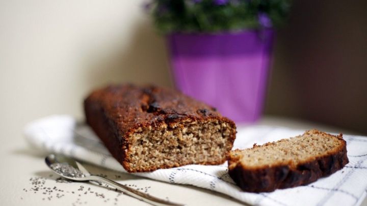 Ein saftiges Bananen-Chiabrot liegt auf einem Geschirrtuch, w&auml;hrend eine Scheibe daneben liegt, umgeben von einem bl&uuml;henden Topfpflanze.