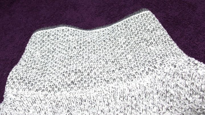 Der Mohairpullover mit seiner feinen Struktur liegt auf einem lila Hintergrund, zeigt eine geringe Fusselbildung.