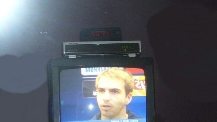 Ein Fernseher zeigt ein Interview in einem Schlafzimmerambiente mit einem Spiegel im Hintergrund.