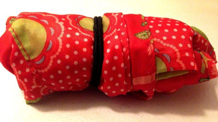 Eine faltbare Einkaufstasche im Etui liegt zusammengerollt auf einer Oberfl&auml;che, bereit f&uuml;r den n&auml;chsten Einkauf.