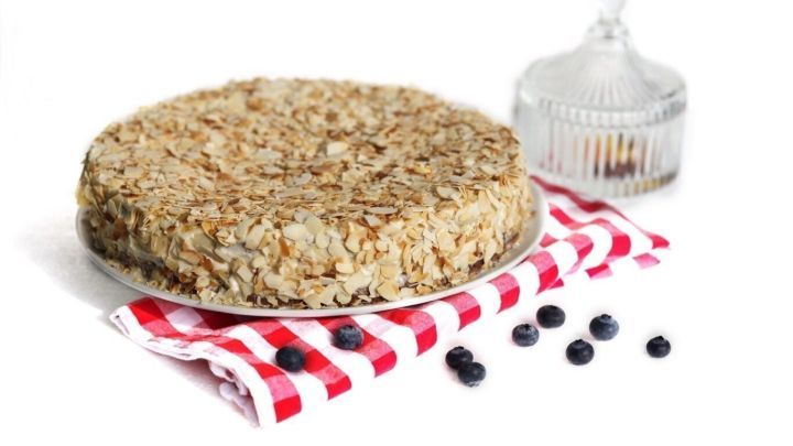 Ein Blitzkuchen liegt auf einem rot-wei&szlig; gestreiften Tuch, umgeben von einigen Heidelbeeren und einer Glasglocke.