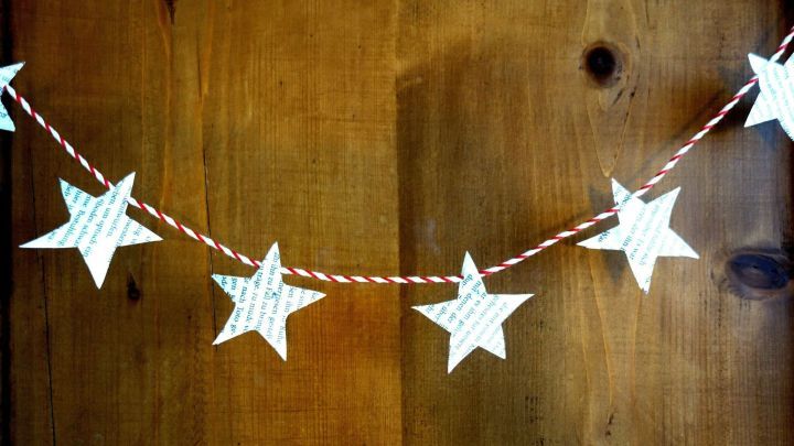 Eine Wimpelkette aus wei&szlig;en Sternen h&auml;ngt an einer Schnur vor einer Holzoberfl&auml;che und verleiht einem Raum eine festliche Stimmung.
