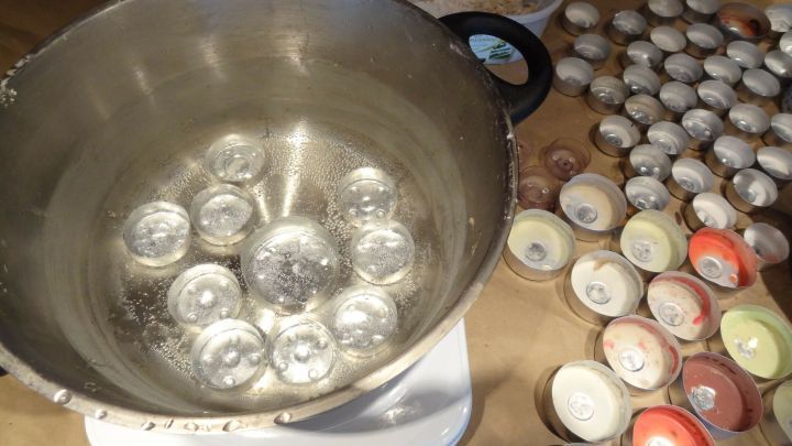 Teelichth&uuml;llen liegen um eine Sch&uuml;ssel mit erhitztem Wasser, w&auml;hrend sie vorbereitet werden, um sie wiederzuverwenden.
