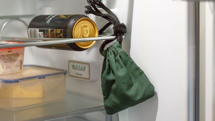 Ein gr&uuml;ner Beutel h&auml;ngt in einem K&uuml;hlschrank, daneben eine Dose, die auf Ger&uuml;che im K&uuml;hlschrank hinweisen k&ouml;nnte.