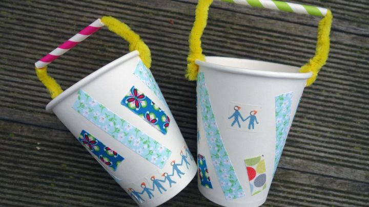 Bunte Kaffeebecher mit bunten Griffen stehen auf einem Tisch und zeigen kreative Osternest-Dekorationen.