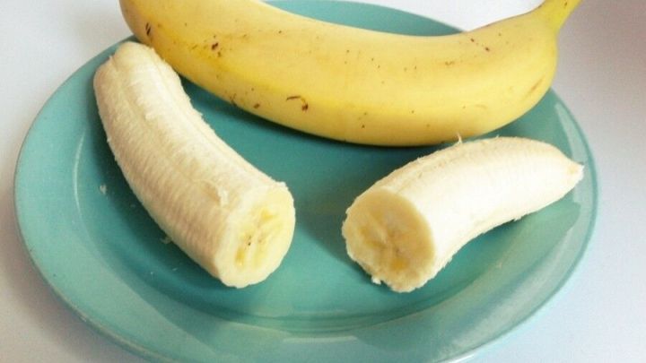 Eine ganze Banane und zwei halbierte Bananen liegen auf einem t&uuml;rkisfarbenen Teller und zeigen die gesunde Pracht der Bananen.