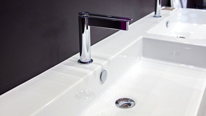 Ein modernes Kunststoffwaschbecken mit gl&auml;nzender Oberfl&auml;che steht an einem dunklen Wandhintergrund, bereit zur Reinigung von Verf&auml;rbungen.