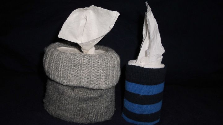 Ein Notfall-Taschentuchspender steht auf einem dunklen Hintergrund. Die Spender sind aus Stoff, einer grau und einer gestreift.