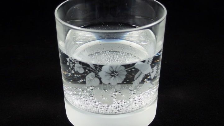 Ein transparentes Glas mit sprudelndem Wasser steht auf einem dunklen Hintergrund, ideal f&uuml;r mehr Trinken aus kleinen Gl&auml;sern.