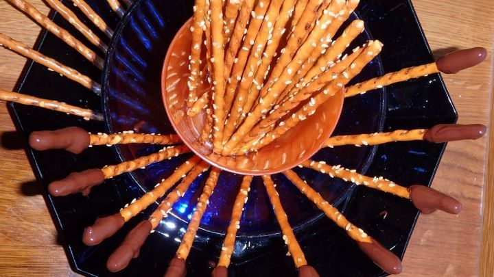 Sesamsalzstangen mit dunkler Schokolade stehen kreativ auf einem Teller, umgeben von einem dunklen, dekorativen Hintergrund.