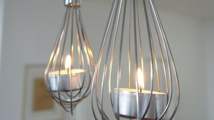 Teelichter leuchten im dekorativen Schneebesen, der elegant von der Decke h&auml;ngt und eine moderne Atmosph&auml;re schafft.