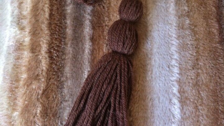 Verzierte Quasten liegen auf einem hellen, gestreiften Stoff, w&auml;hrend eine weitere Quaste in der N&auml;he sichtbar ist.